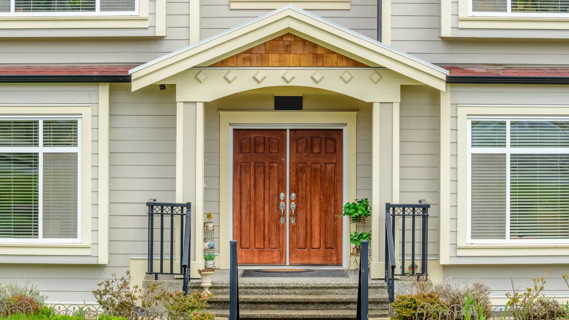 Elegant home entrance featuring a double wooden door with ornate handles. Flanked by tall windows, the entryway exudes a welcoming, classic charm.