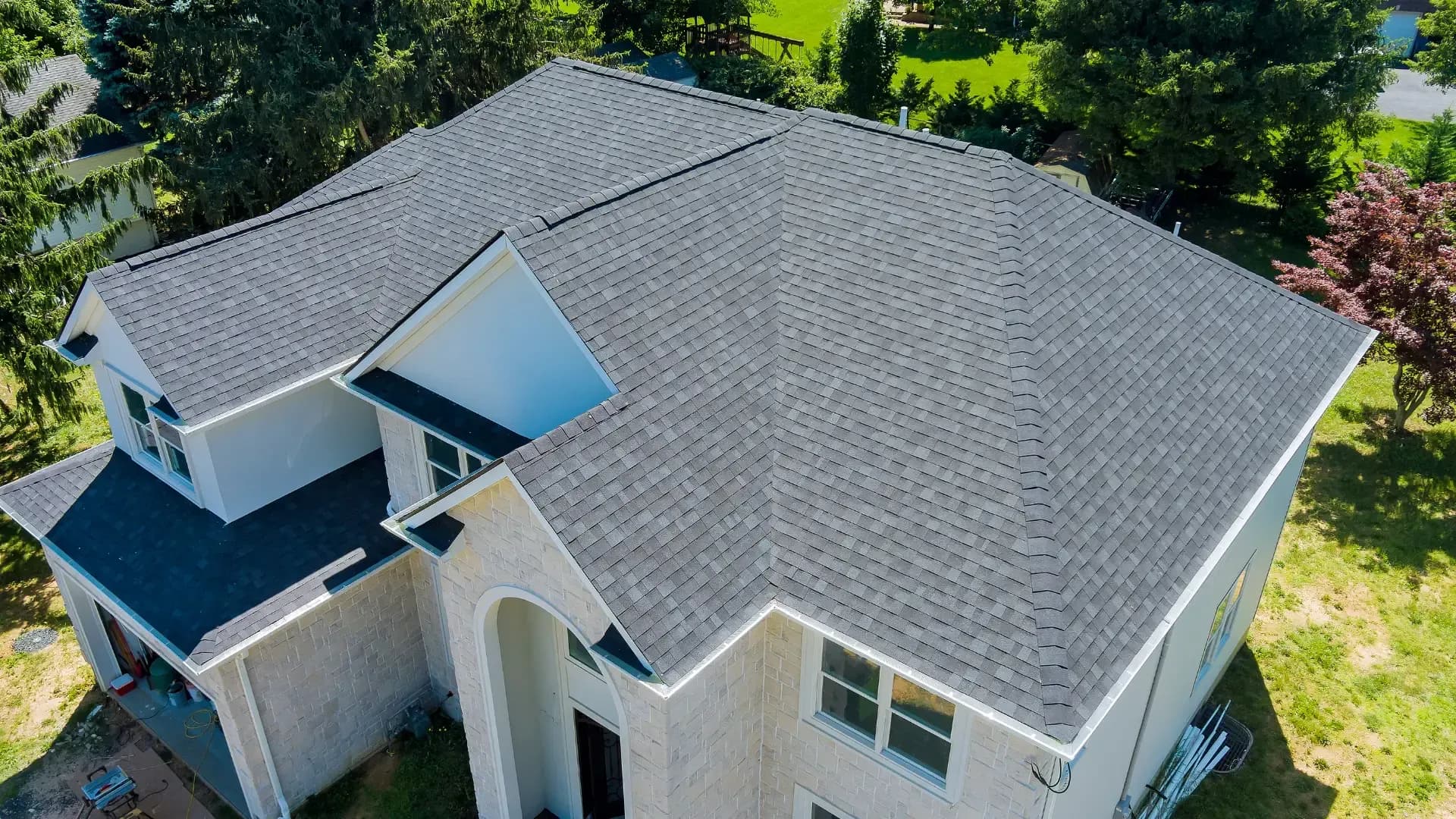 Aerial view of a large home with a newly installed gray asphalt shingle roof.