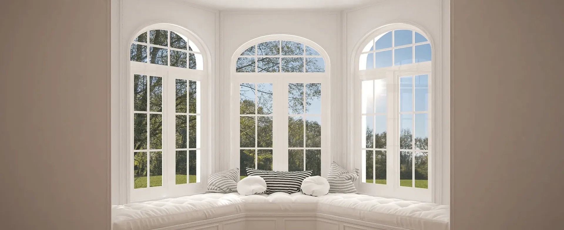 Bright window seat surrounded by three large arched windows with white frames and views of a green landscape.