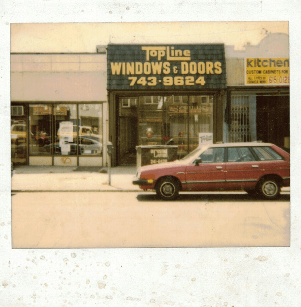 Vintage photo of a TopLine Windows & Doors storefront with a red station wagon parked in front.